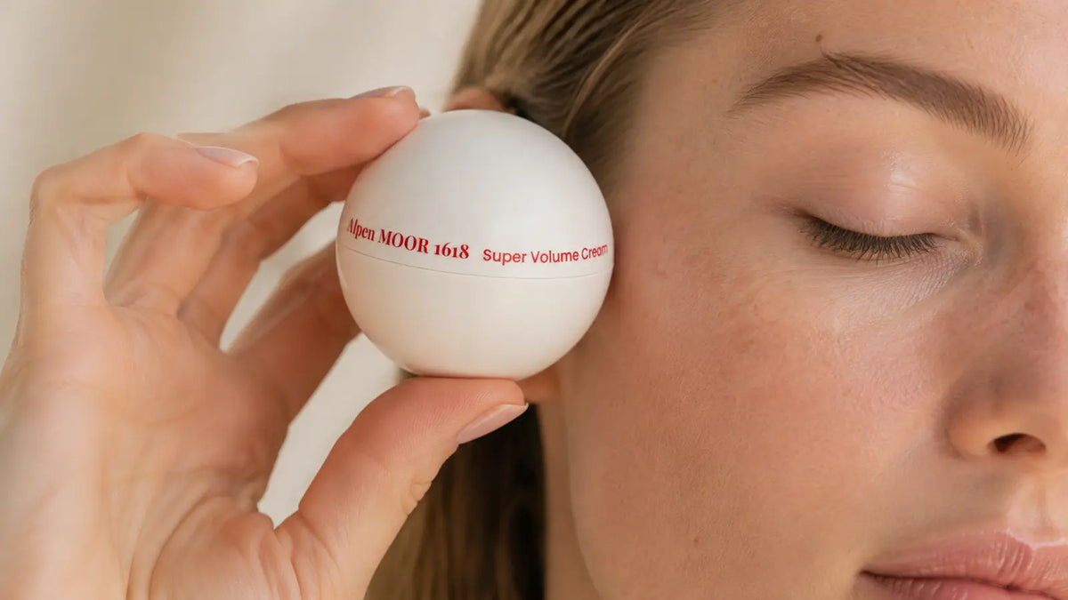 Close portrait of a woman holding Super Volume Cream near her temple in a calm, static pose