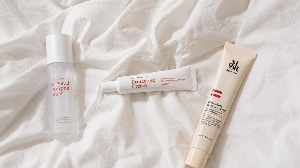 Crystal Ampoule Mist, Protecting Cream, and Glow Lifting Radiance Cream arranged together on white linen in soft morning light