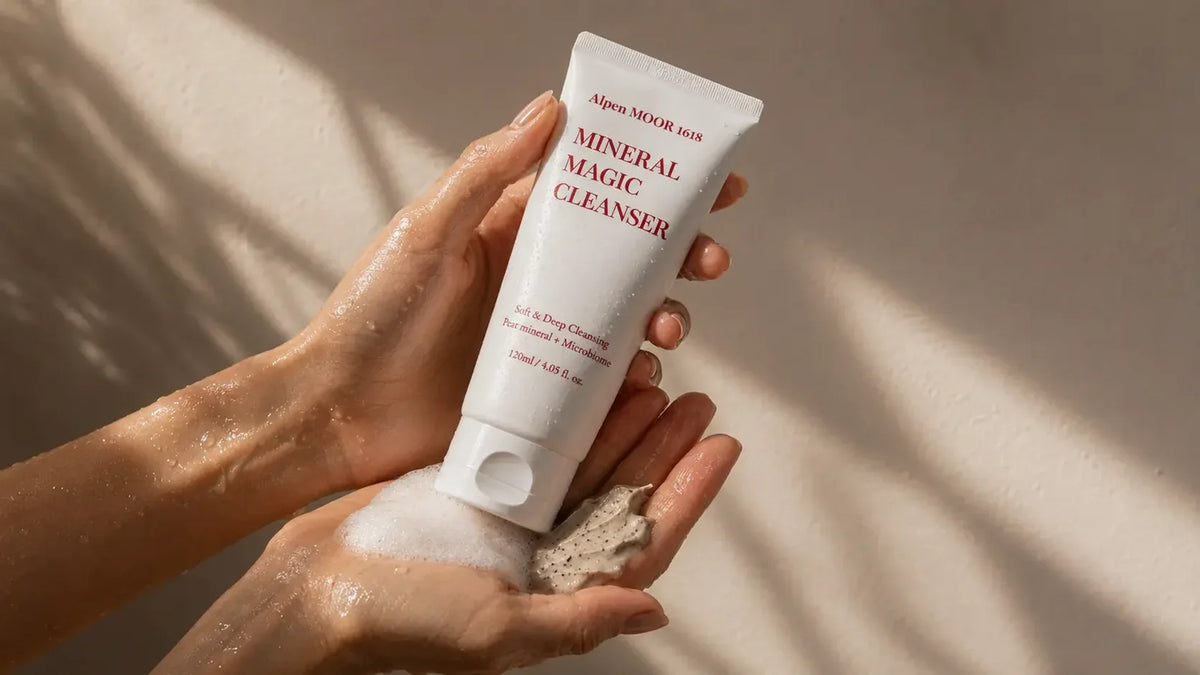 Alpen MOOR 1618 Mineral Magic Cleanser tube held between wet hands working up a soft lather