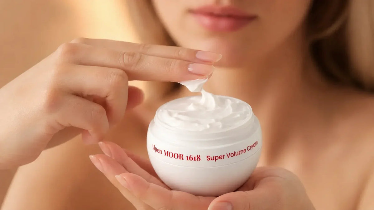 Woman scooping Alpen MOOR 1618 Super Volume Cream from the open jar with one fingertip