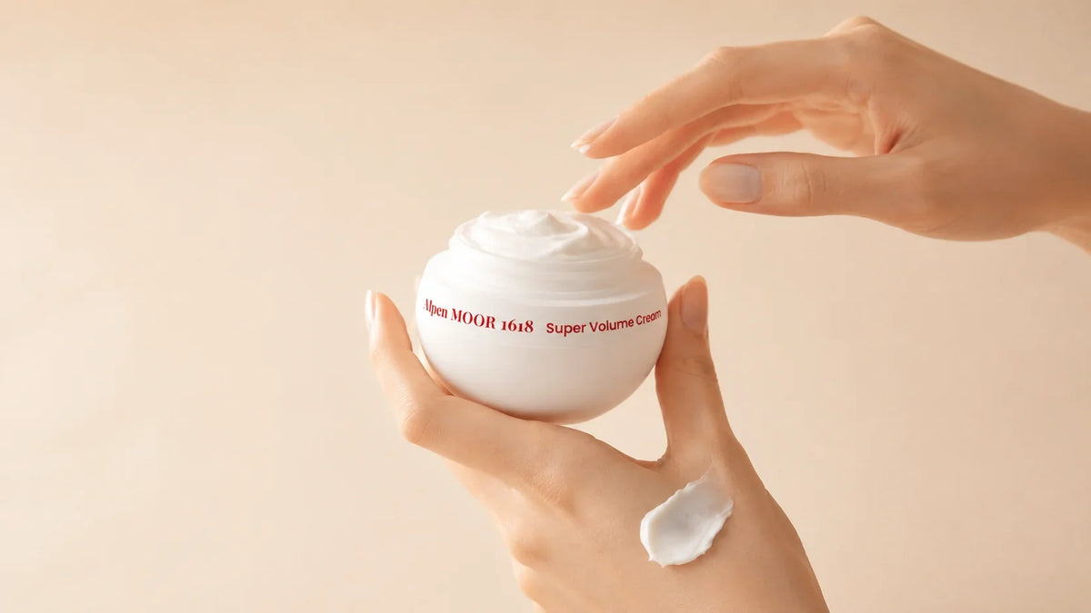Hand dipping a fingertip into an open jar of Alpen MOOR 1618 Super Volume Cream