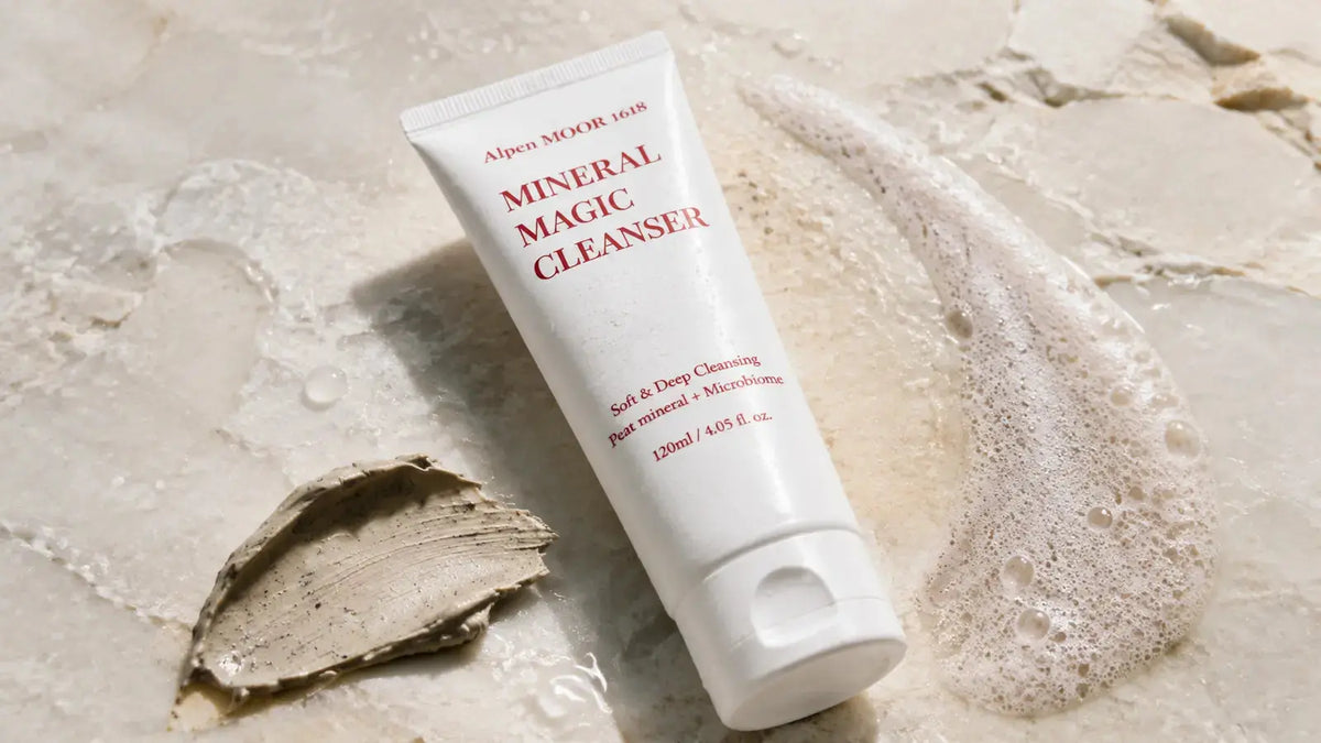 Alpen MOOR 1618 Mineral Magic Cleanser with water droplets, pale foam, and a speckled peat-mineral mound for premium anti-aging cleansing.