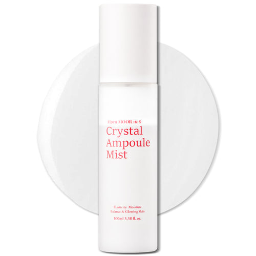 White pump bottle of Crystal Ampoule Mist standing on a round white podium against a plain background.